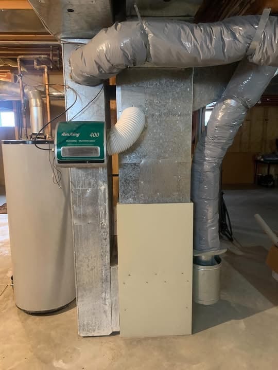 Basement utility area with a water heater, metal ductwork, flexible insulated ducts, and a green Air King 400 humidifier attached to the duct.
