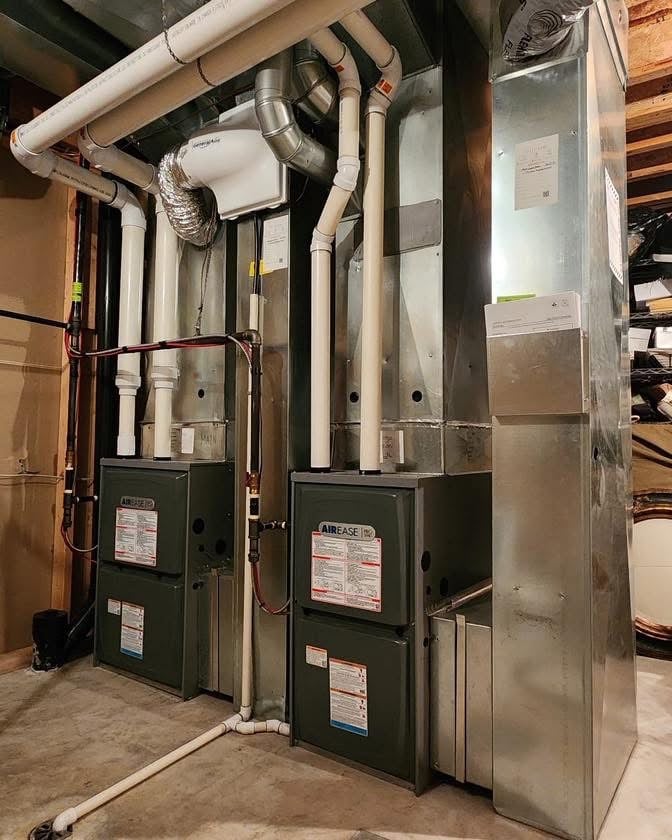 Two Airease brand HVAC units with connected white and metal ductwork installed in a basement.