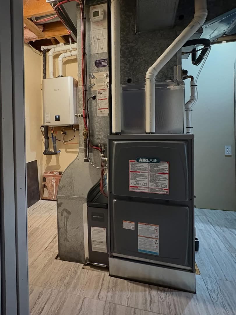 Basement utility area featuring an Airease furnace and white tankless water heater mounted on the wall.