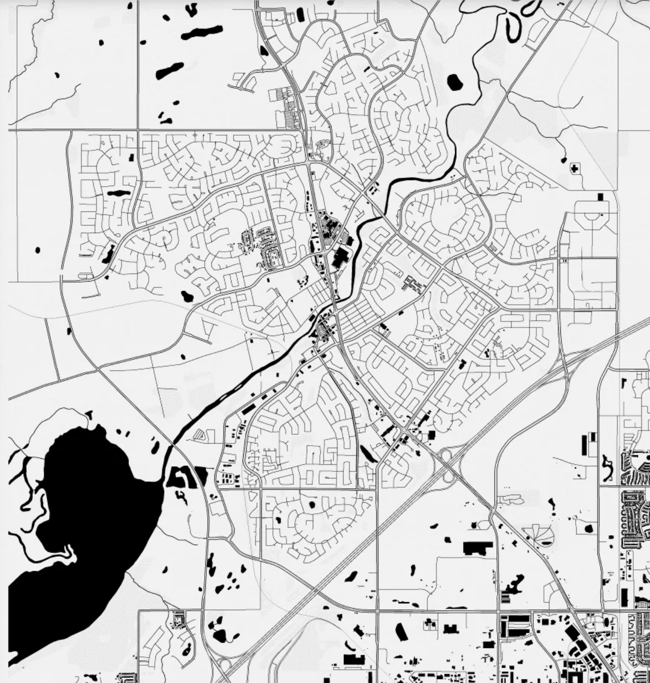 Black and white map showing detailed streets, residential areas, a river running through the center, and a large water body on the left side.
