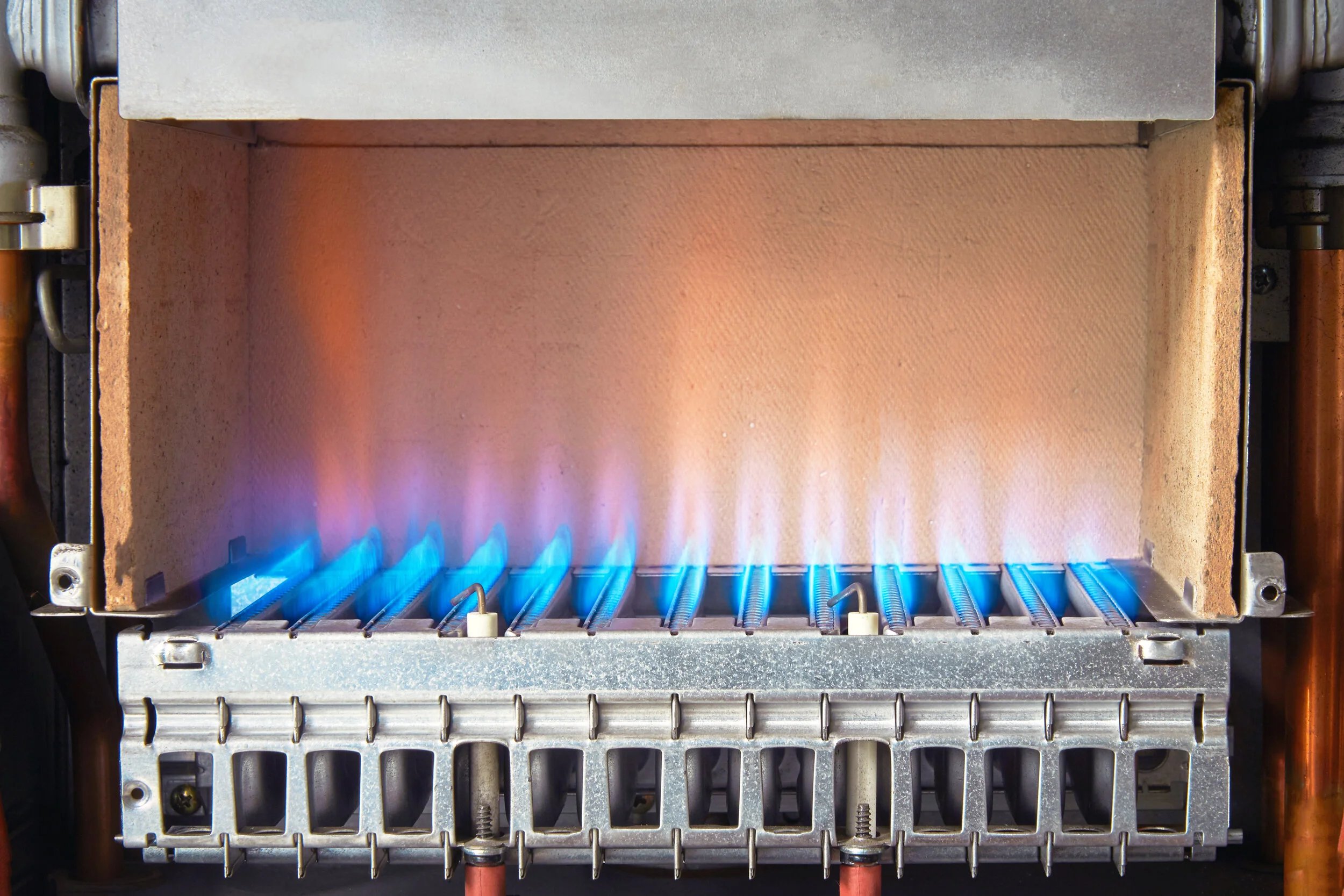Blue gas flames burning evenly across a furnace burner inside a heating system.