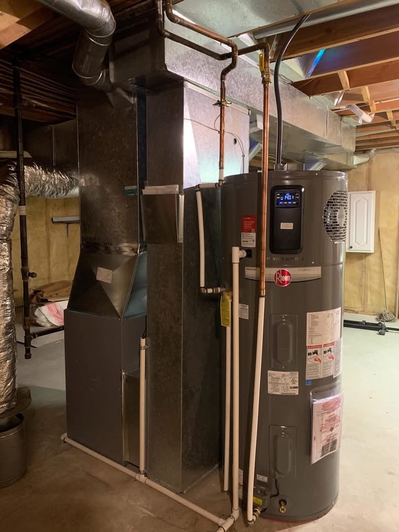 Gray Rheem water heater and HVAC duct system installed in a basement with exposed ceiling beams and concrete floor.