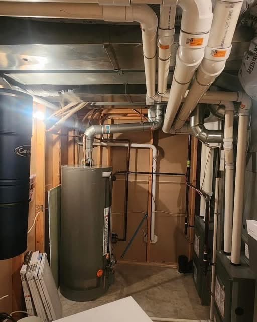 water heater tank install with pipes and ducting running in the basement