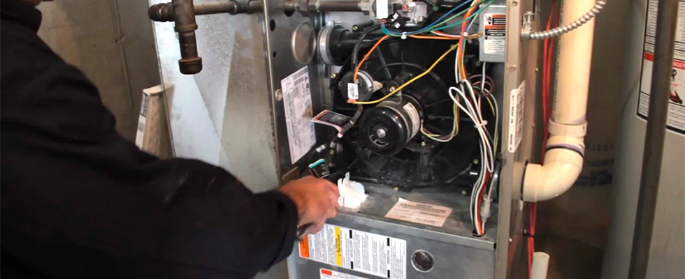 stock photo of a tech fixing wiring inside of a furnace